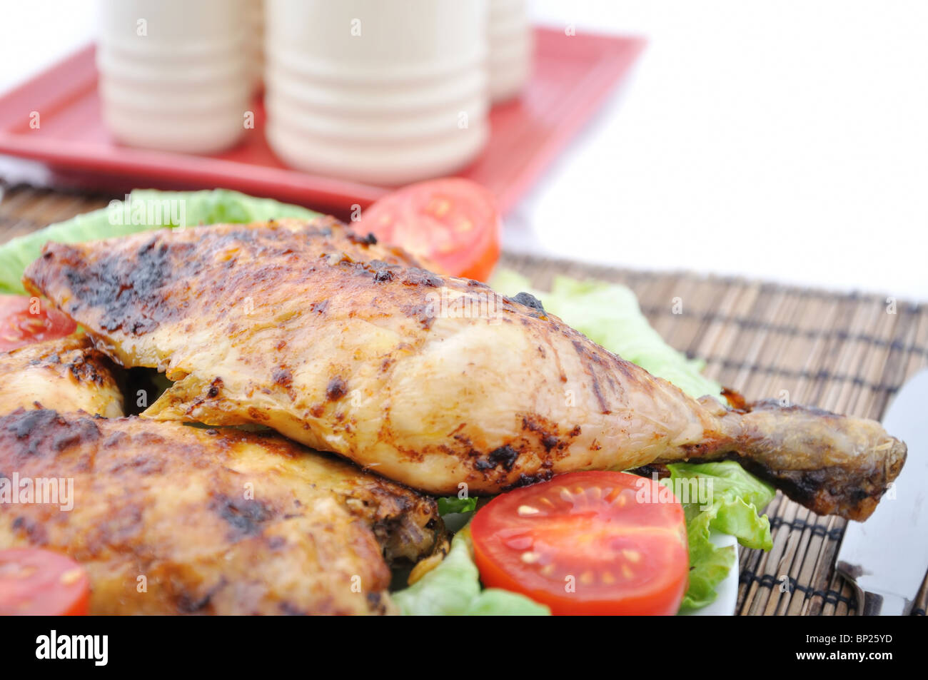 Roasted chicken drumsticks and vegetables and saltshaker Stock Photo