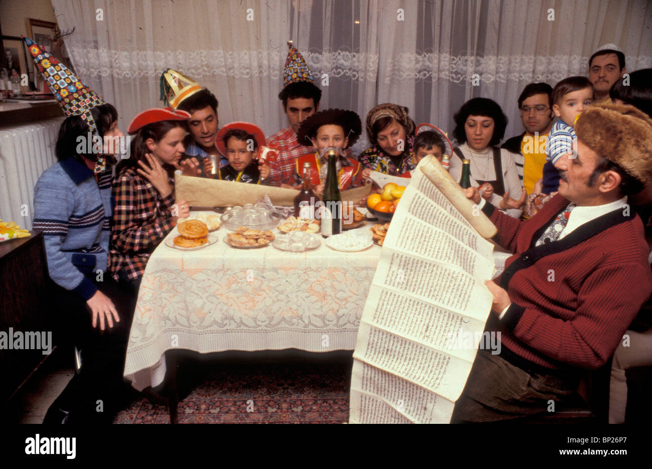 1234. PURIM - A FAMILY ORIGINATING FROM IRAQ READING THE ESTER SCROLL, NOTE THE CHILDREN DRESSED UP FOR THE FEAST Stock Photo
