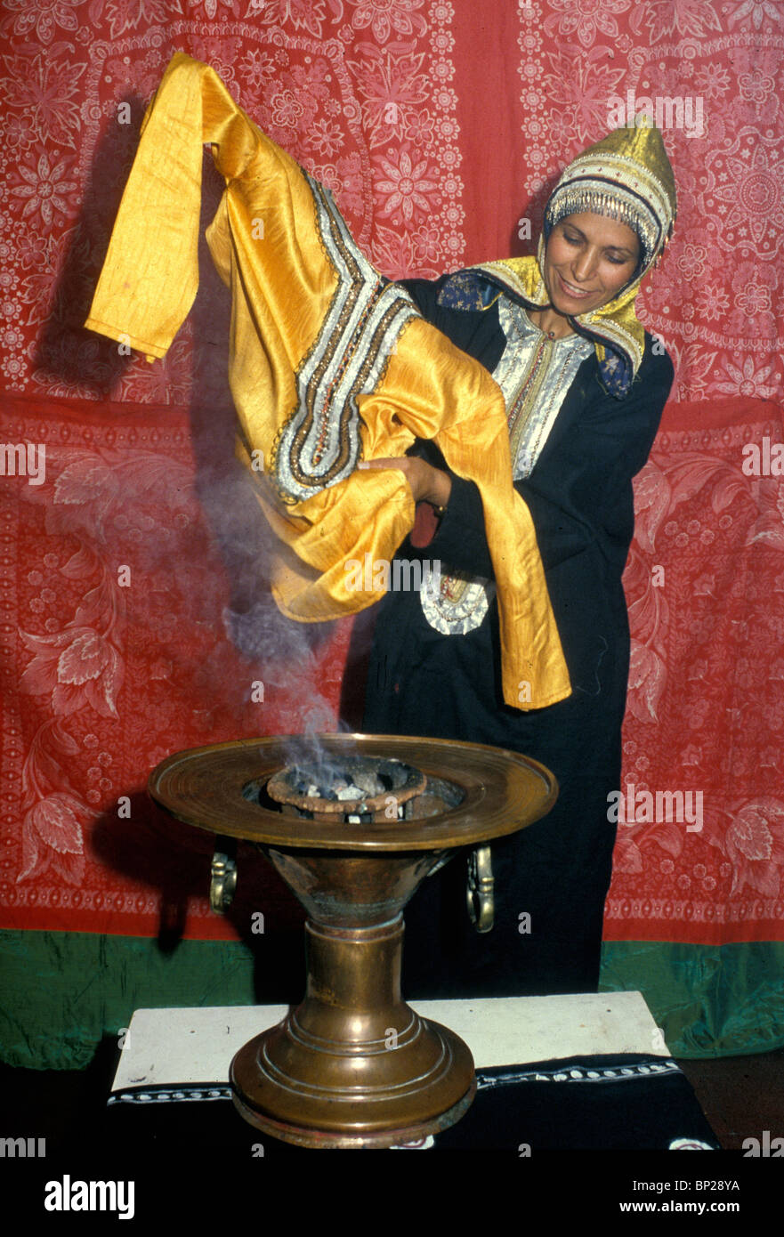 PERFUMING SHABBAT CLOTHES - A YEMENITE-JEWISH WOMAN BURNS INCENSE ON FRIDAY AFTERNOON TO GIVE HER SABBAT CLOTHING & THE ROOMS Stock Photo