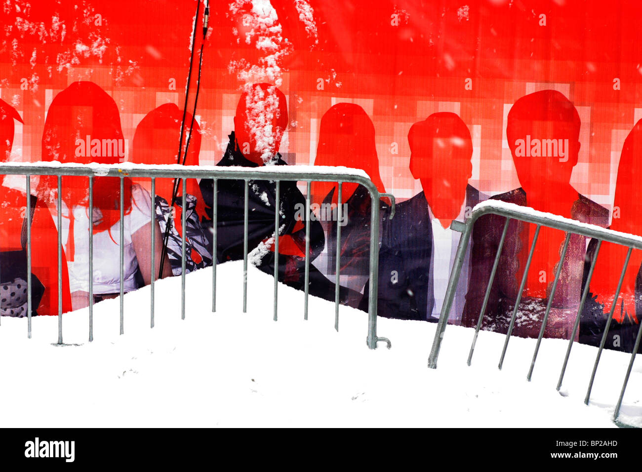 Red poster showing a group of men and women with no faces, set behind a fence covered in snow, New York City, USA. Stock Photo