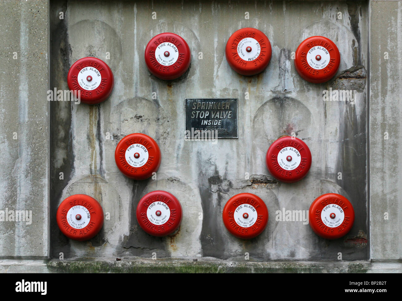 Ten red and white fire alarms on a grey concrete wall in London, UK. Stock Photo