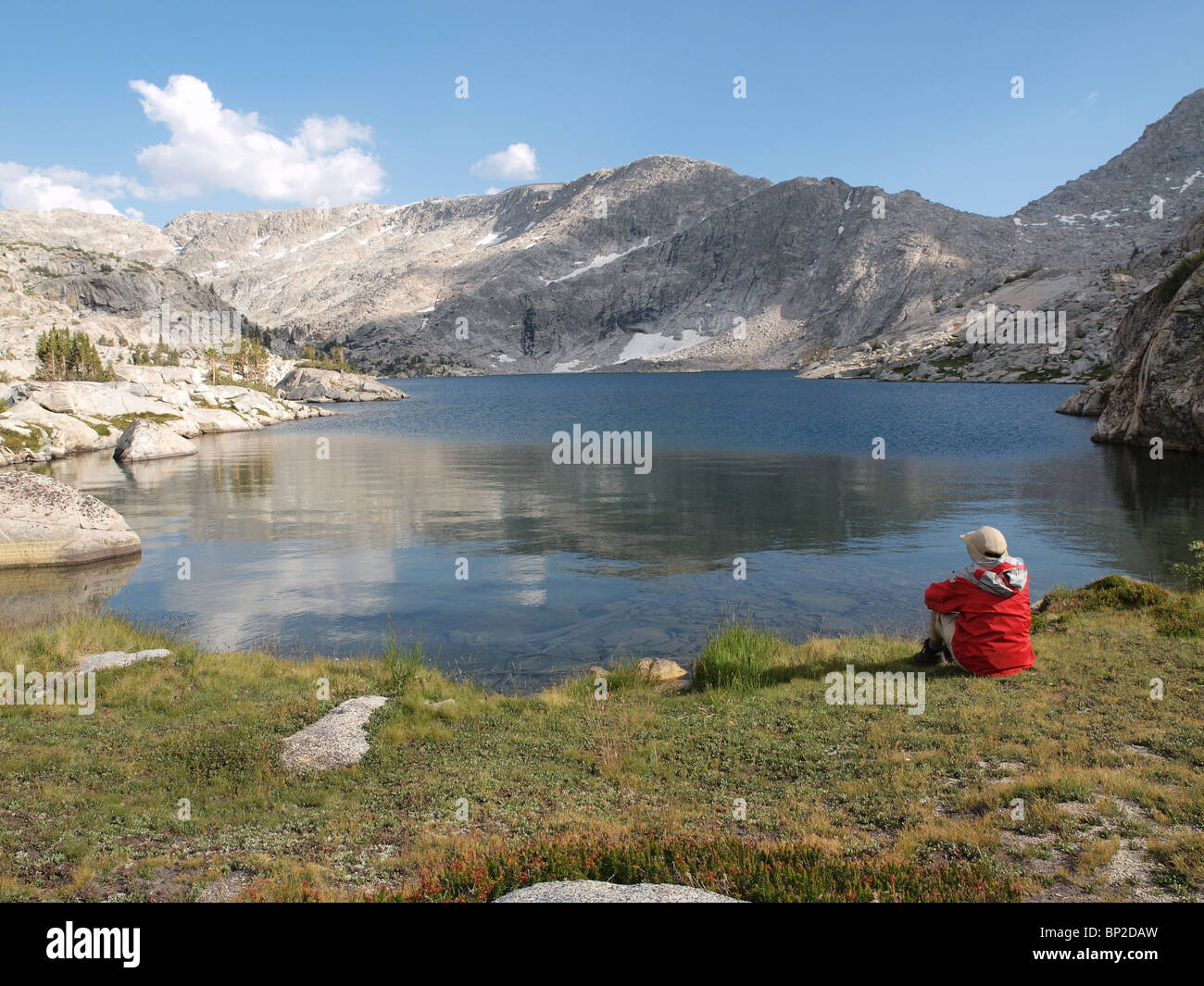 A hiker overlooks 10,568' Three Island Lake in the John Muir Wilderness of the Sierra National Forest. Stock Photo
