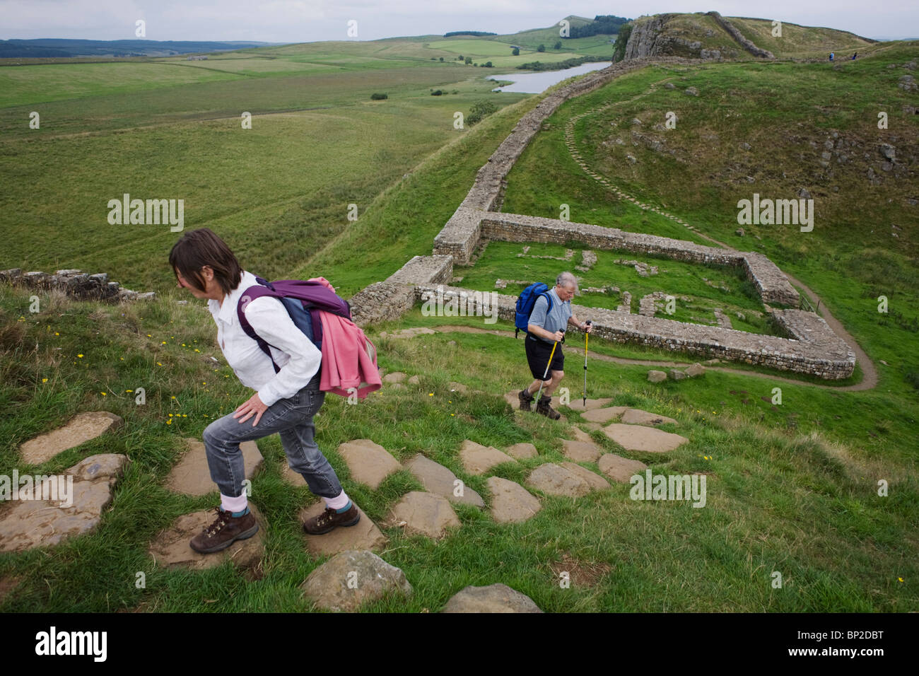 Walkers walk above Milecastle 39 on Roman Hadrian's Wall, once the northern frontier of Rome's empire from Barbarian tribes. Stock Photo
