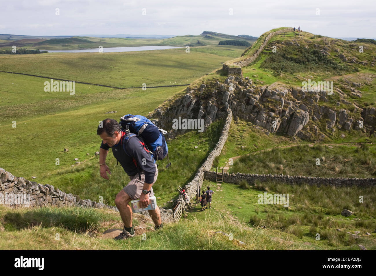 Walker climbs steep path on Roman Emperor Hadrian's Wall, once the northern frontier of Rome's empire from Barbarian tribes. Stock Photo