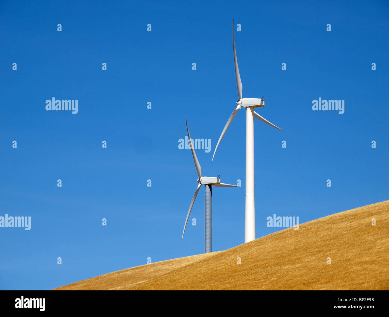 Two modern windmills on a grassland knoll. Stock Photo