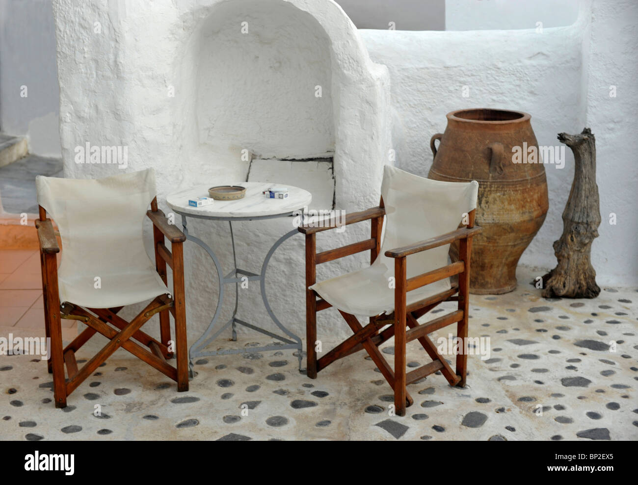 Attractive patio with two directors chairs and table outside a café at Oia on the Greek island of Santorini in the Cyclades Stock Photo