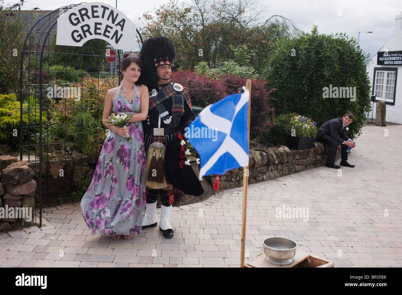 Family stands with Scottish piper at Gretna Green, where Britain's wedding couples converge on for a quickie marriage. Stock Photo