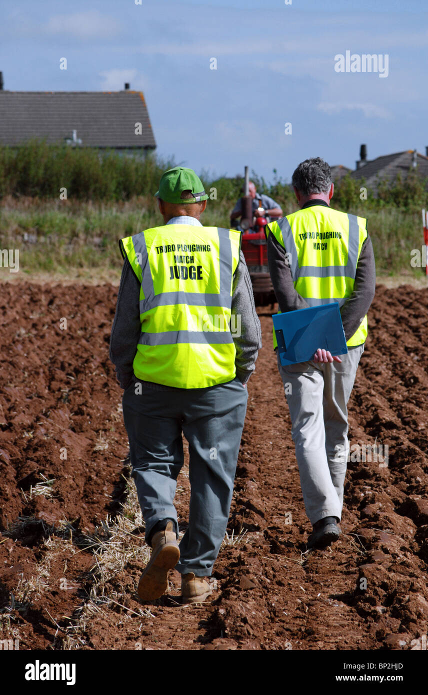 two judges examining the furrows at a ploughing match near truro in cornwall, uk Stock Photo