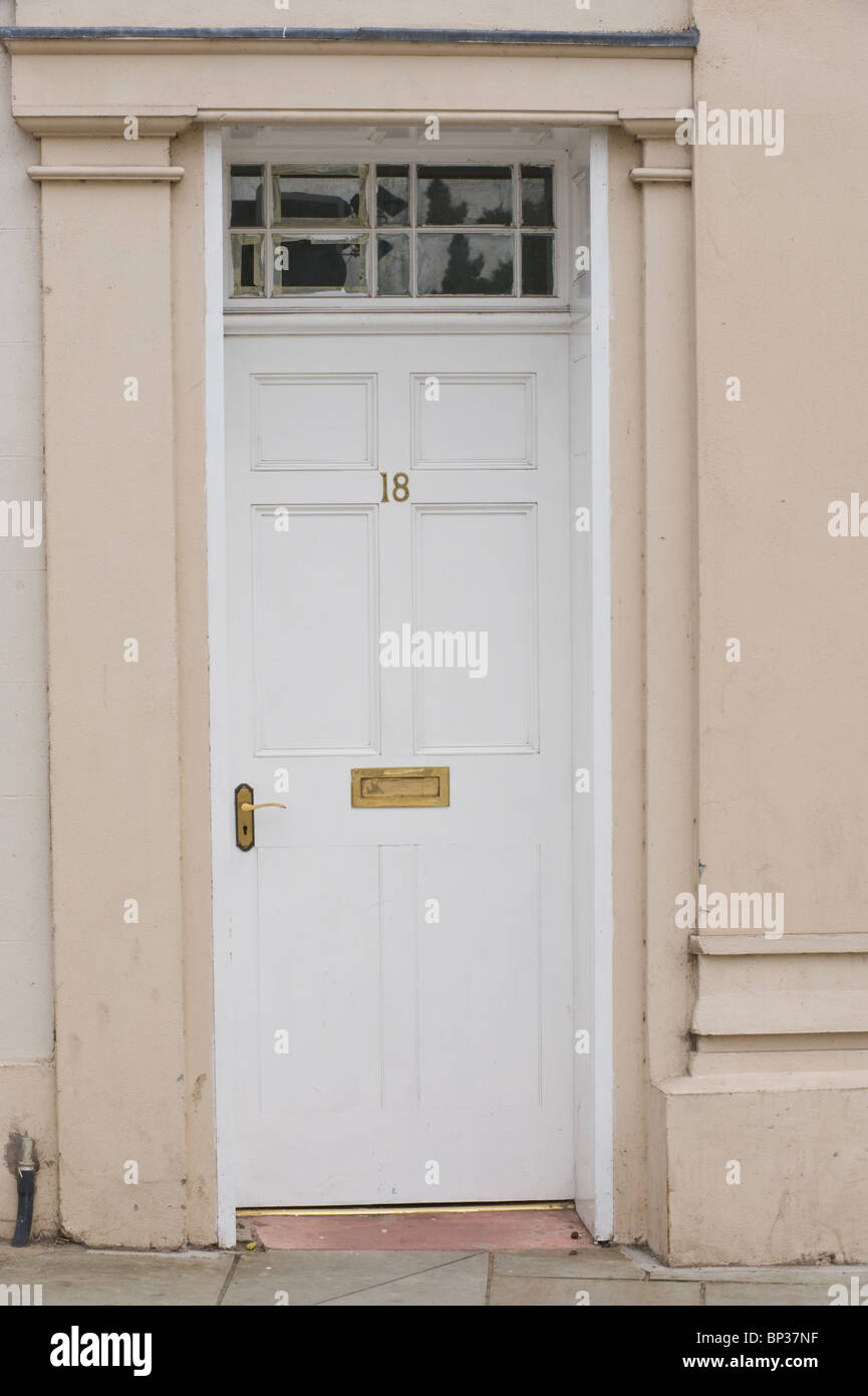 White painted wooden paneled front door no. 18 with brass handle letterbox and fanlight of period town house in UK Stock Photo