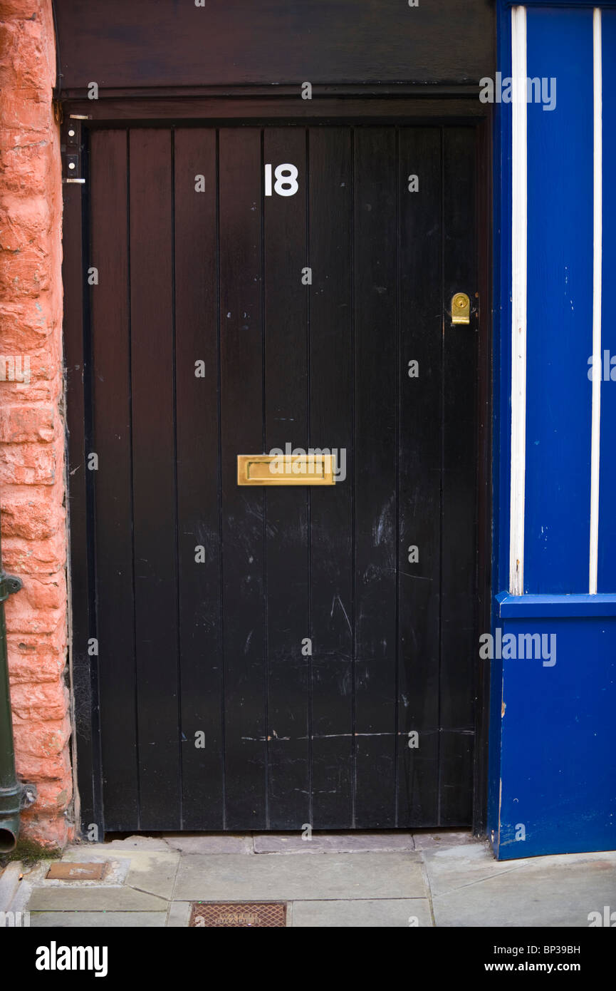 Black painted wooden front door no. 18 with brass letterbox of house in UK Stock Photo