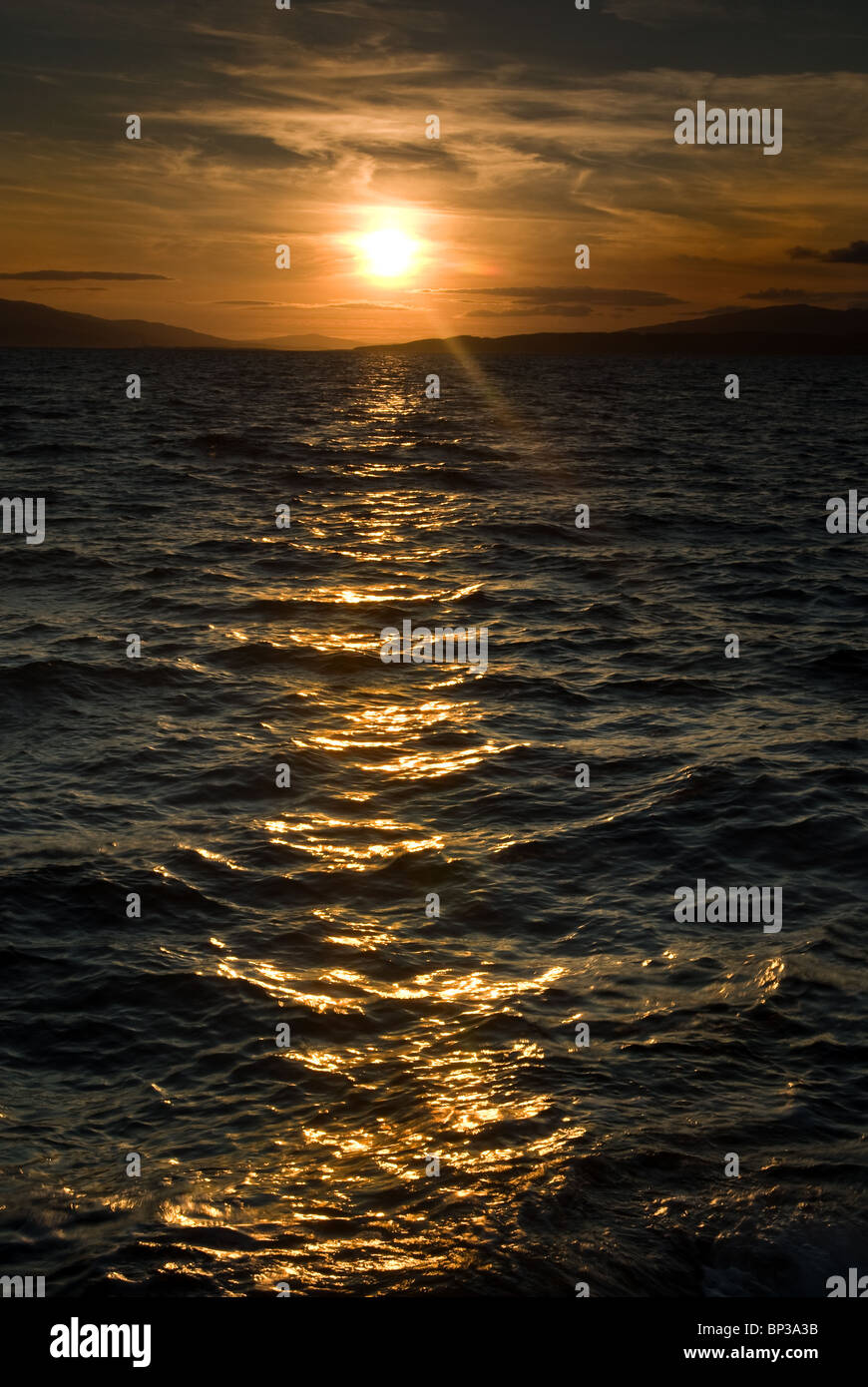 Sun set over choppy seas Stock Photo