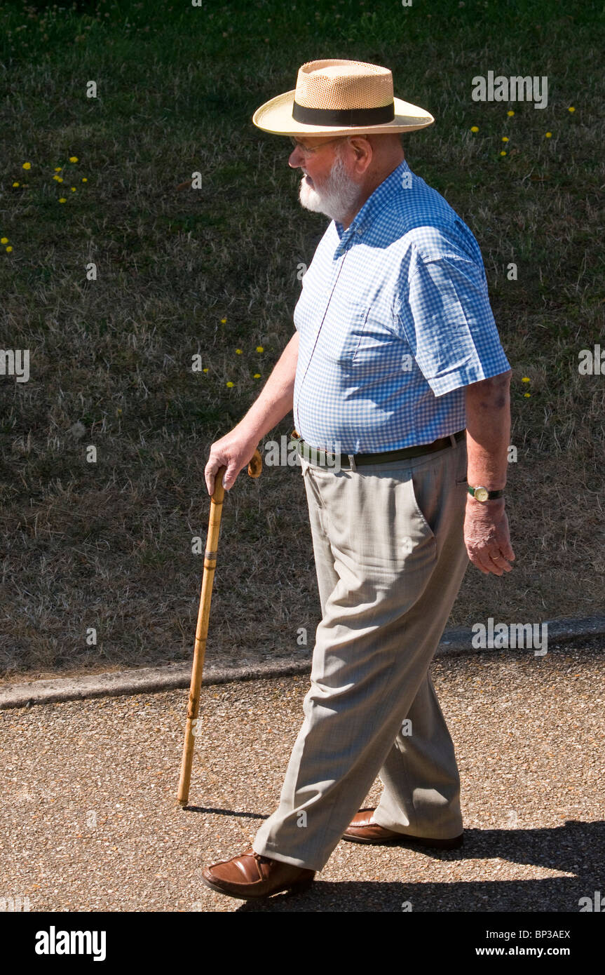 Older man with cane walking on pavement - France. Stock Photo