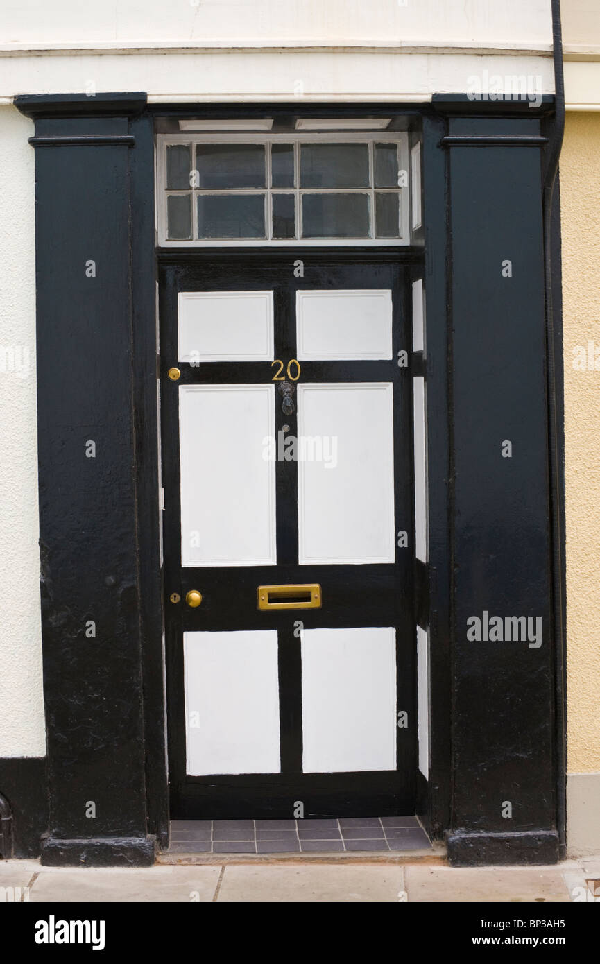 White and black painted wooden paneled front door no. 20 with brass knob letterbox and black surround of period town house in UK Stock Photo