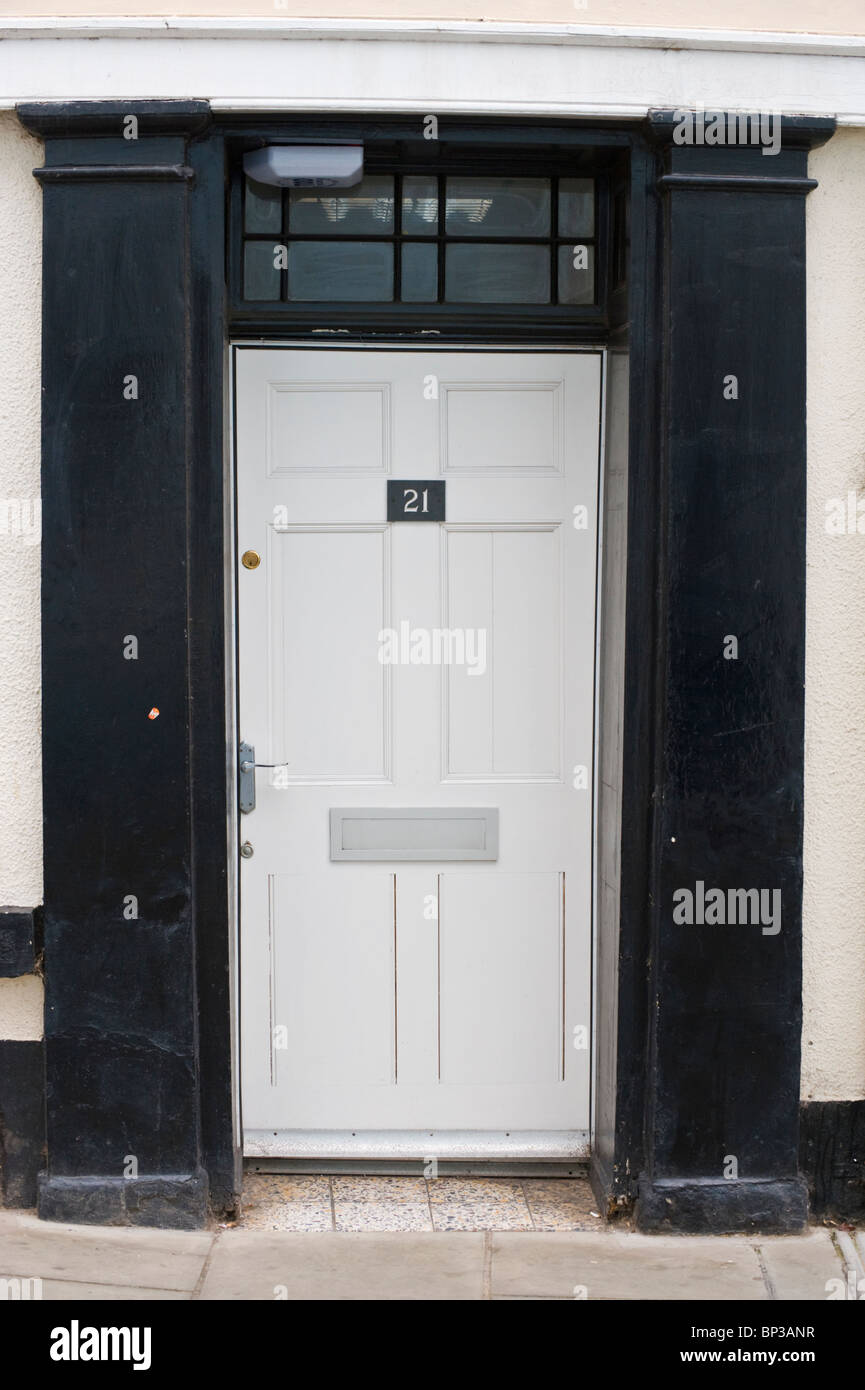 White painted modern wooden paneled front door no. 21 with handle letterbox and black surround of period town house in UK Stock Photo