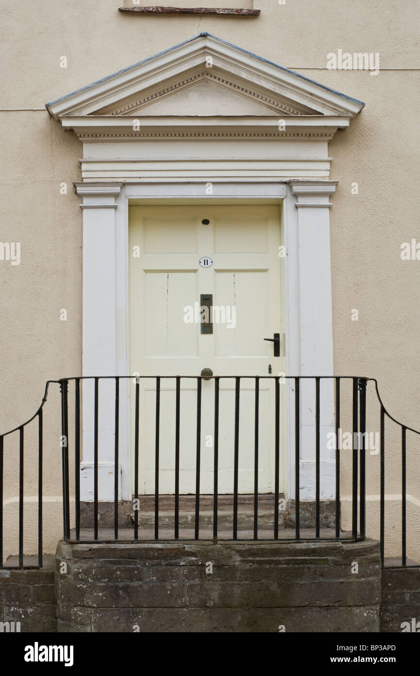 White wooden paneled front door no. 11 with handle letterbox white triangular pediment architrave of Georgian town house in UK Stock Photo