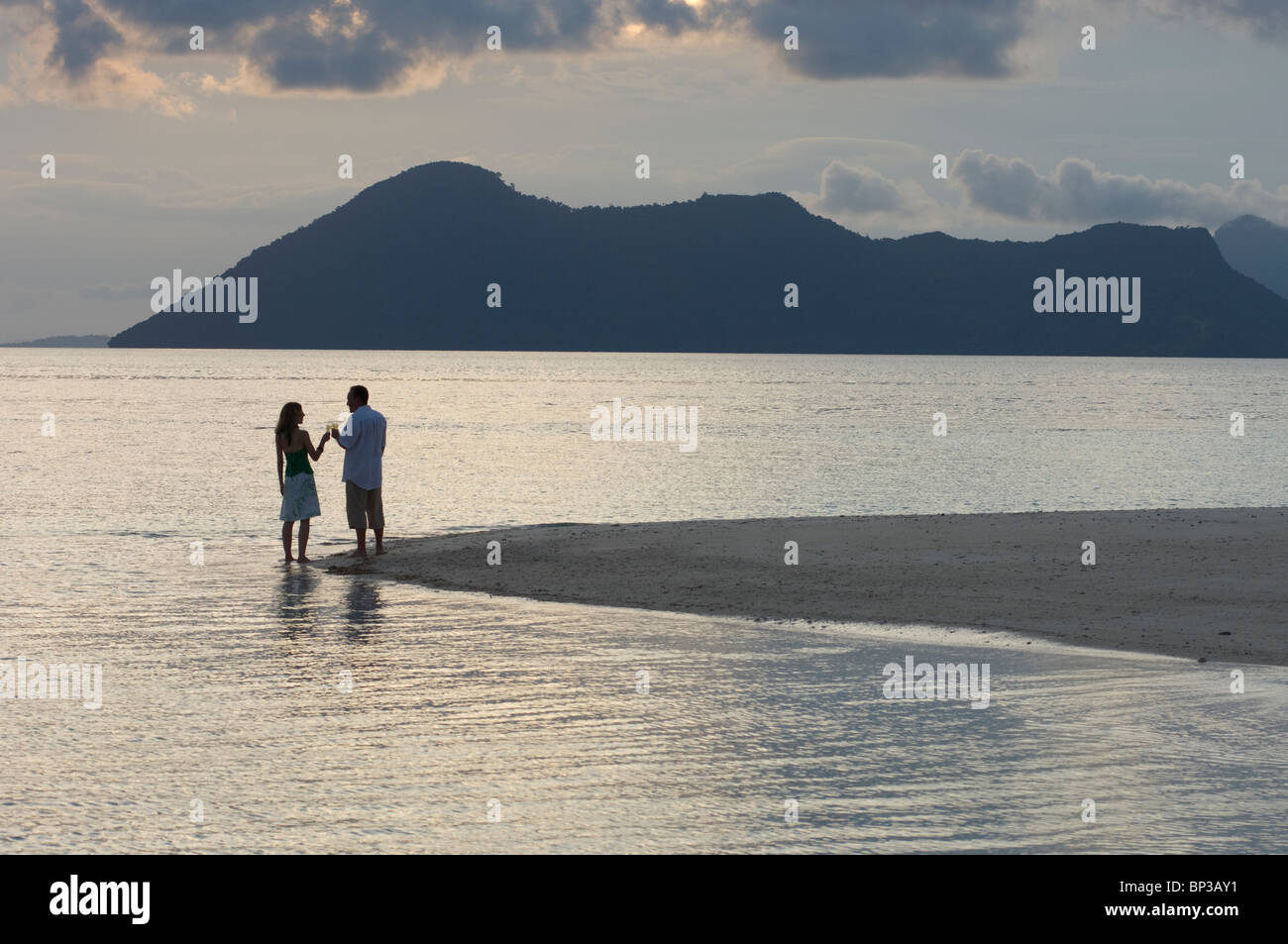 Couple enjoying romantic sunset drinks on the beach, Pom Pom Island Resort, Celebes Sea, Sabah, East Malaysia. Stock Photo