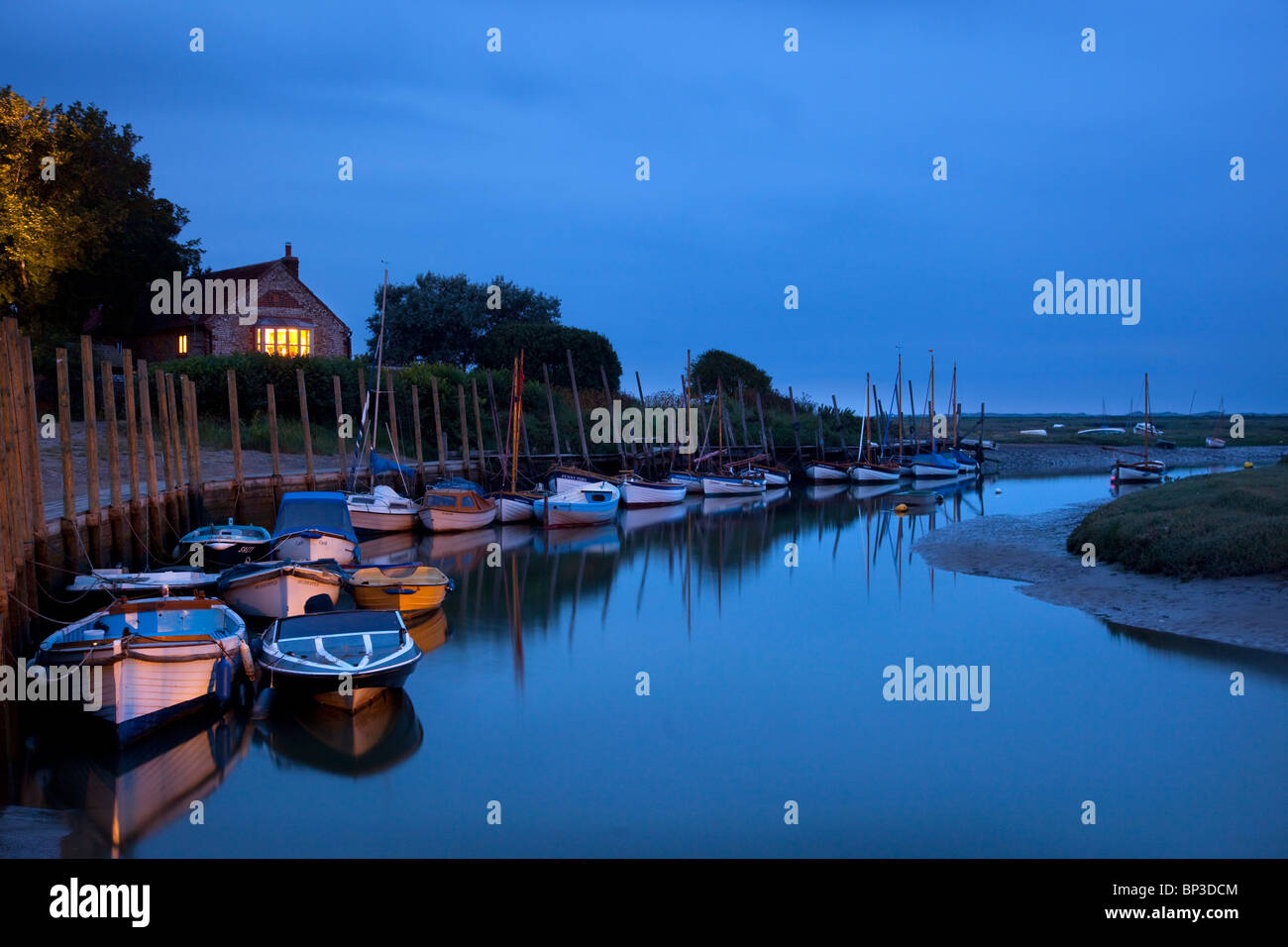 Blakeney quayside at dusk with boats moored up in channel, Norfolk, England Stock Photo