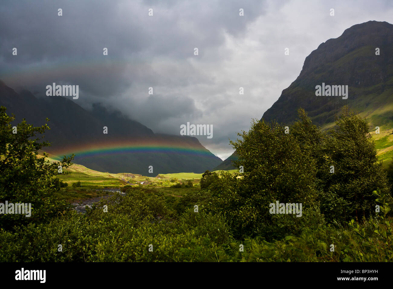 A double rainbow shows against dark clouds in Glencoe, Scotland Stock Photo