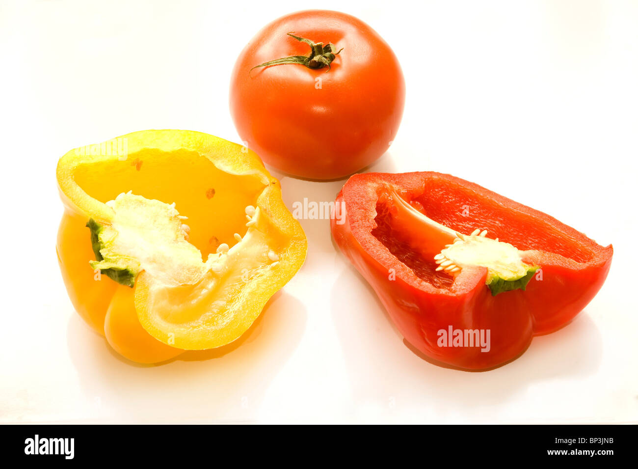 Longitudinal section of yellow and red Bell pepper and a whole tomato set on a white background Stock Photo