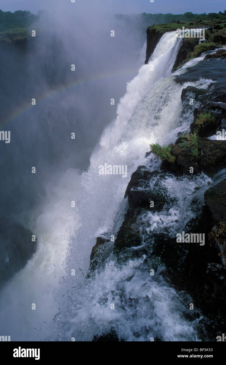 Africa, Zambia, Mosi-Oa-Tunya National Park, Rainbow forms as Zambezi River pours over Main Falls of Victoria Falls Stock Photo