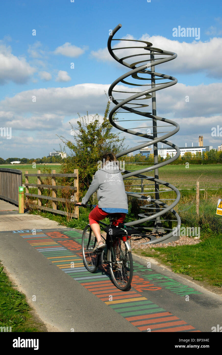 Cyclist passing a double helix artwork by Katy Hallett on the 10,000th mile of the National Cycle Network near Cambridge. Stock Photo