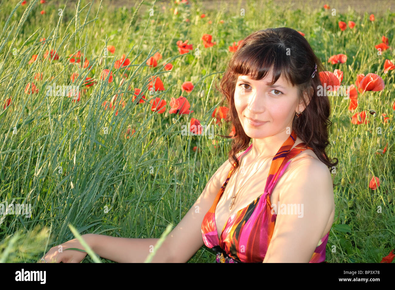 beautiful young woman sits in a poppy field Stock Photo - Alamy