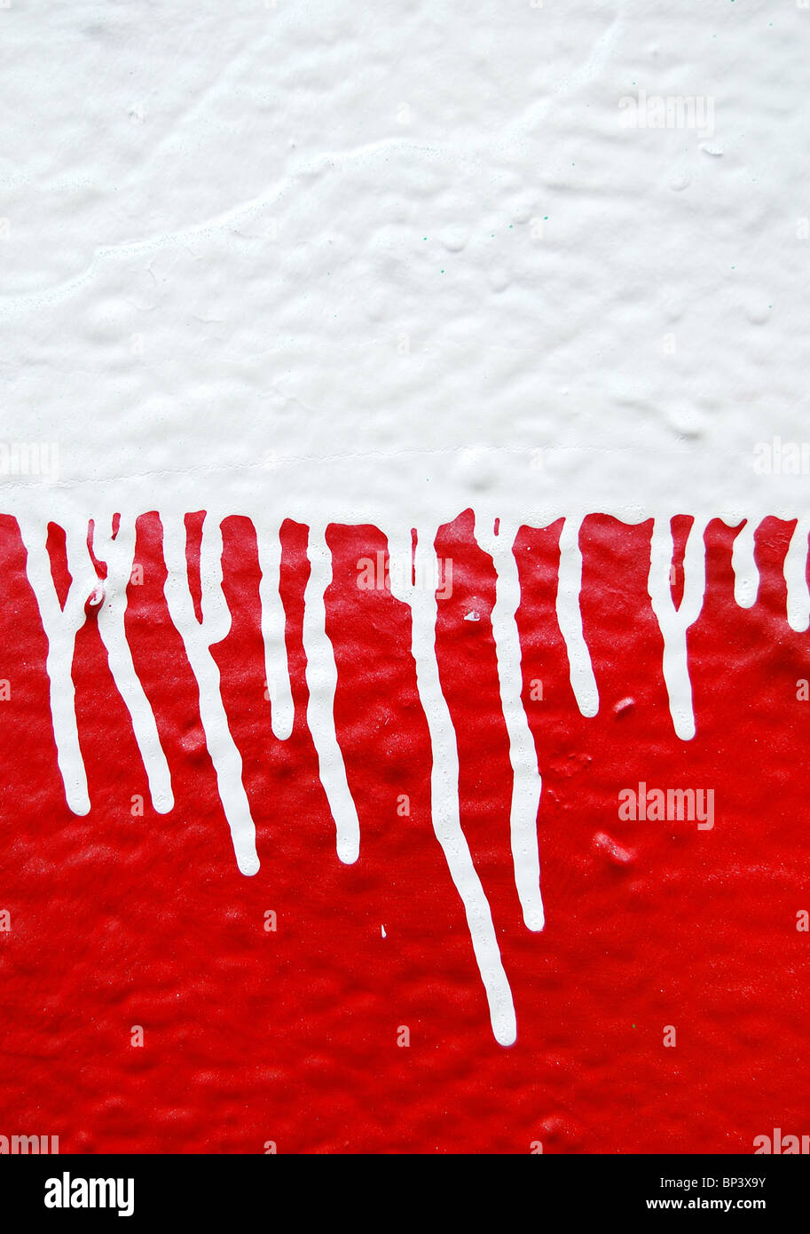 Wall with white dripping paint running over red background. Abstract