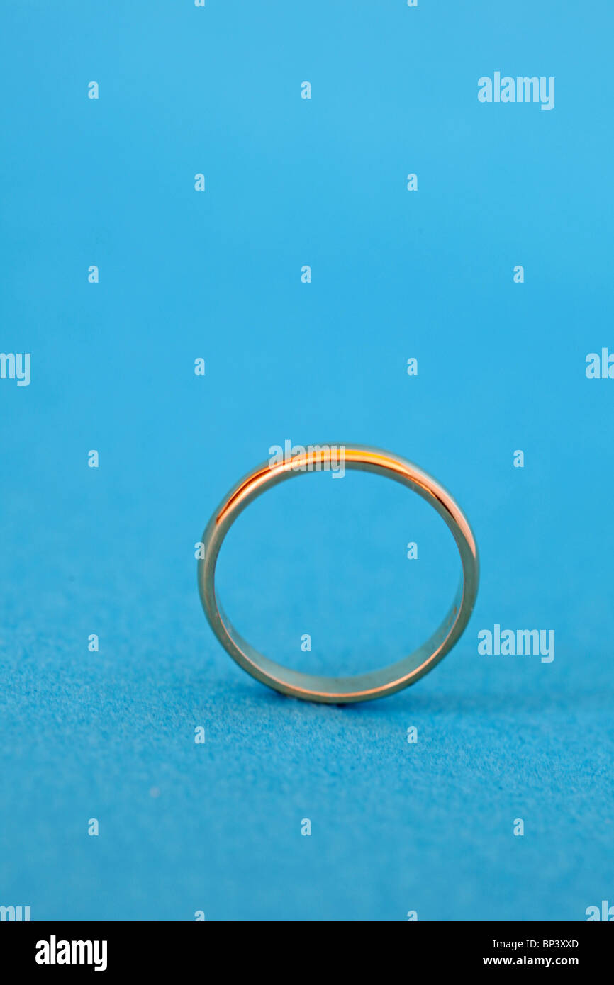 close up of Gold wedding band or ring on blue background Stock Photo