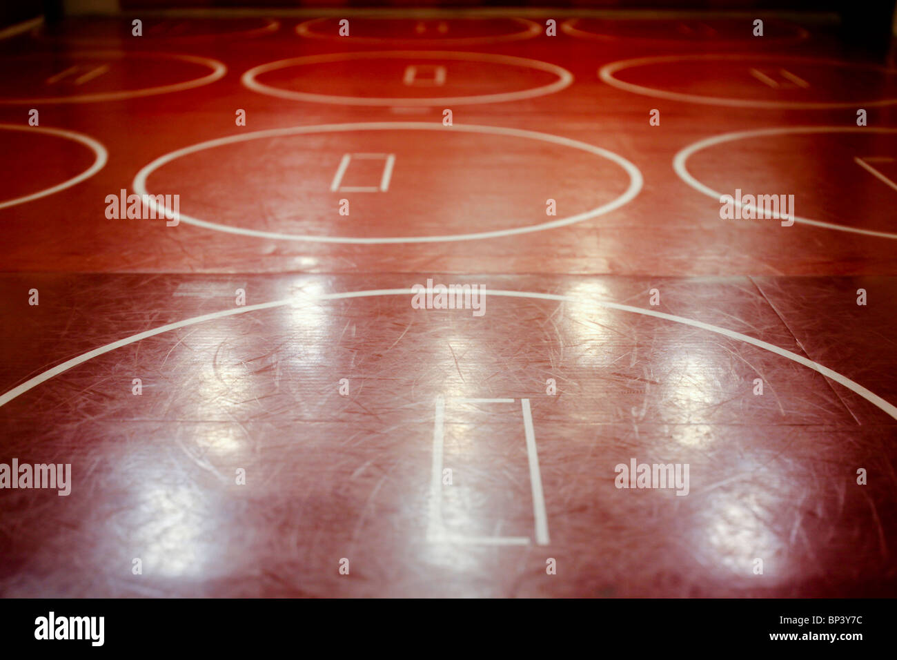 Well worn red school wrestling mat in a gym. Stock Photo