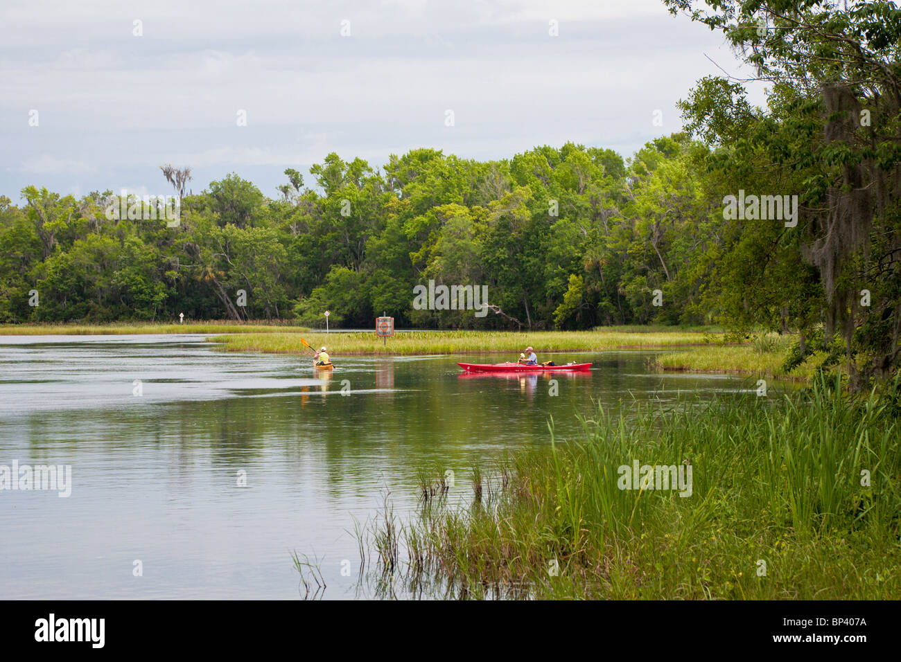 Men rowing bright red and yellow kayaks in the waters at Rainbow Springs State Park in Dunnellon, Florida Stock Photo