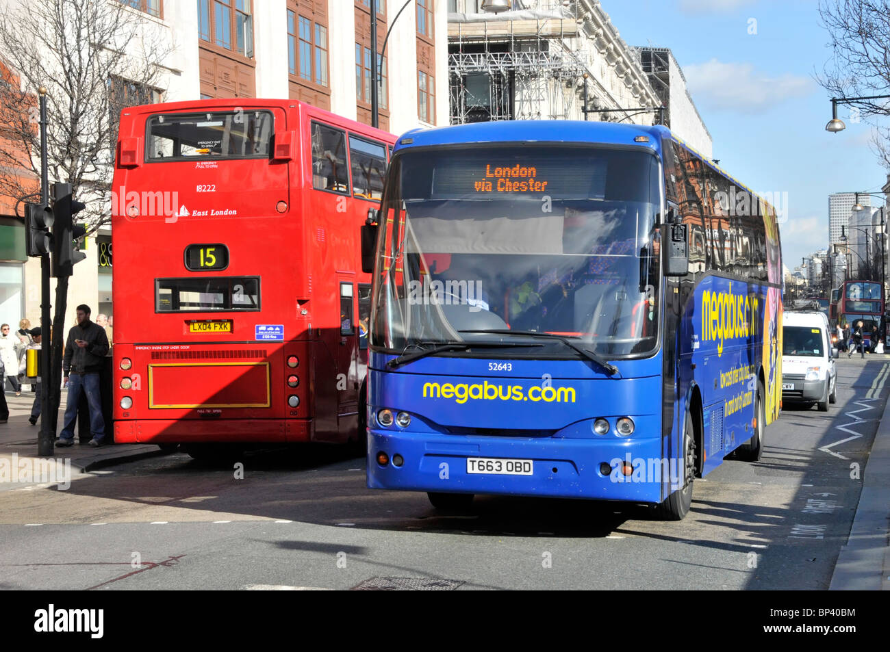 Public transport front view long distance Megabus coach bus arriving in London passing back view of local red double decker route 15 Oxford Street UK Stock Photo