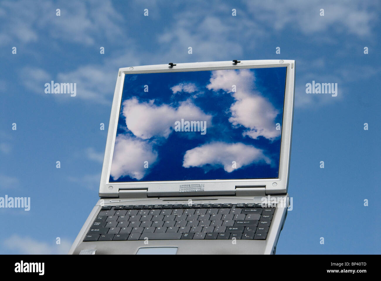 laptop computer with cloud images and clouds in background representing cloud computing Stock Photo