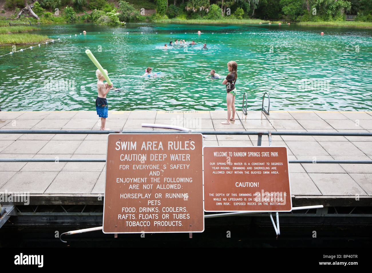 Children playing in designated swimming area behind rules and warning