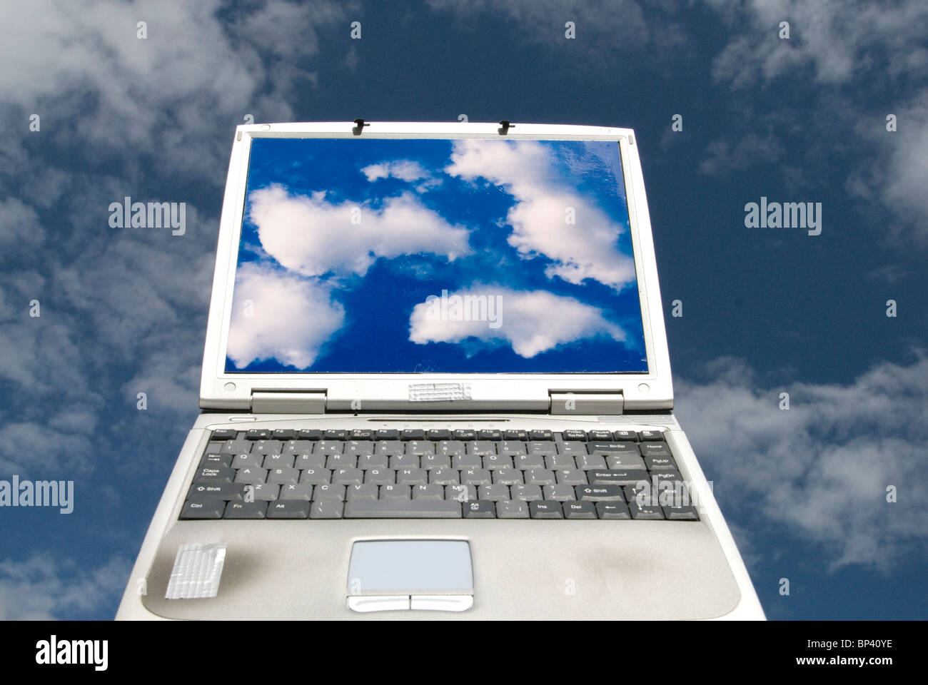 laptop computer with cloud images and clouds in background representing cloud computing Stock Photo