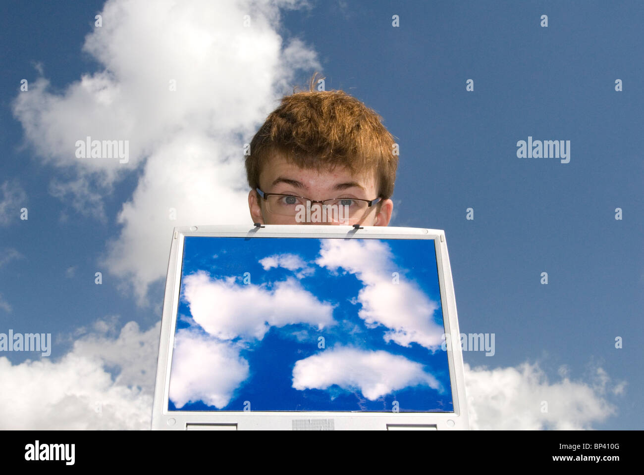 teenager with laptop computer containing cloud images representing cloud computing with clouds in background Stock Photo