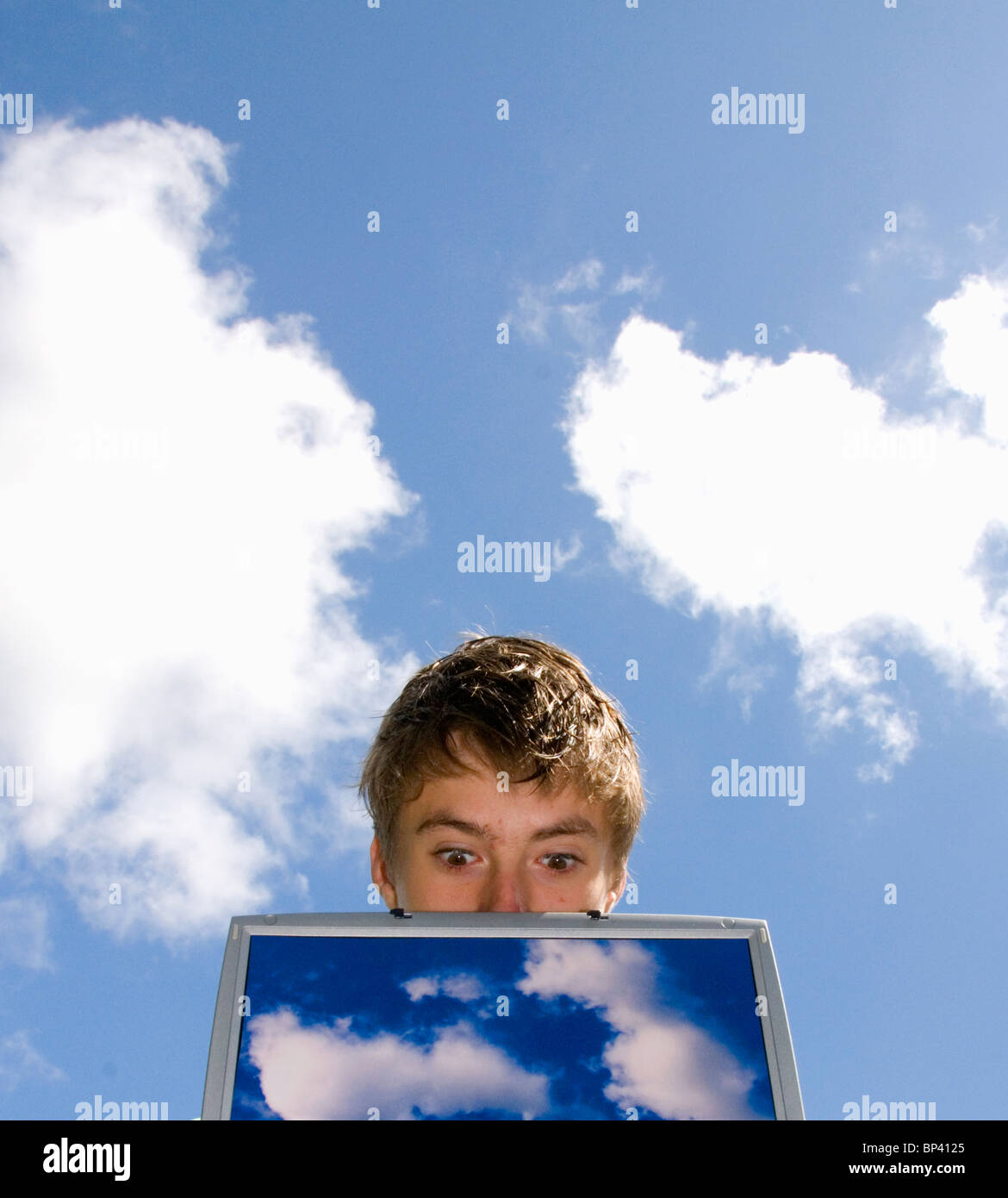 surprised person looking over laptop screen with cloud images representing cloud computing Stock Photo