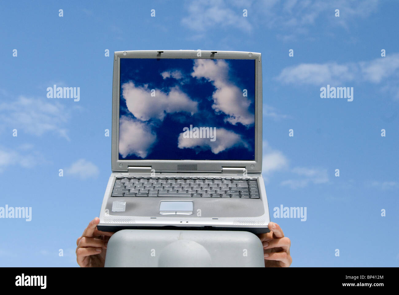 laptop computer with cloud images and clouds in background representing cloud computing Stock Photo
