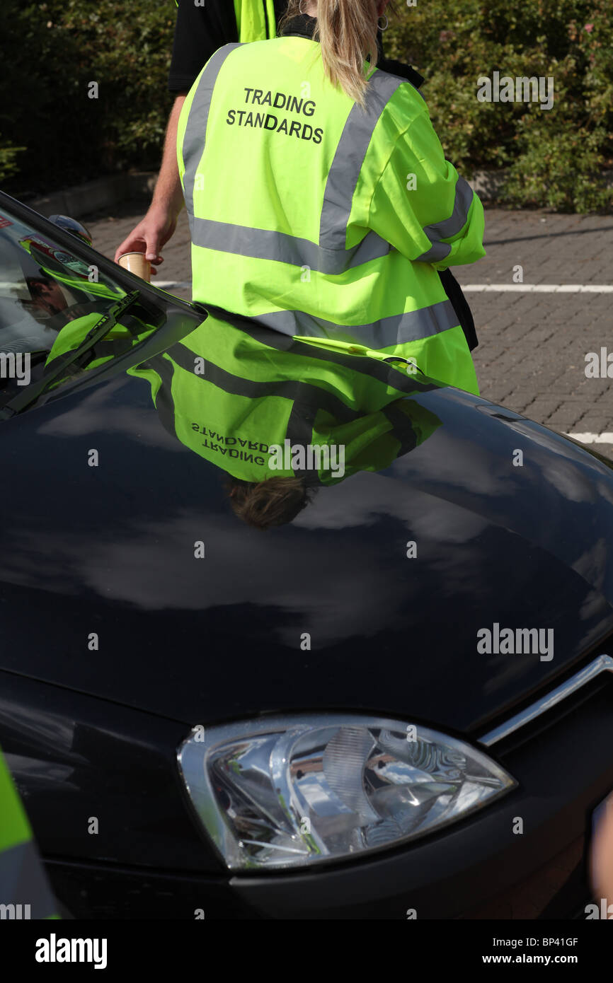 A trading standards officer stood by a car Stock Photo Alamy