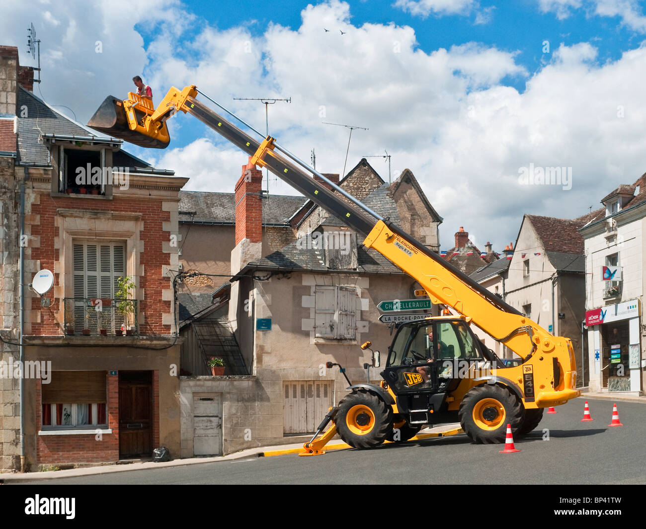 Television aerial being fitted to chimney by man standing (no safety equipment) in JCB Telescopic Handler bucket - France. Stock Photo