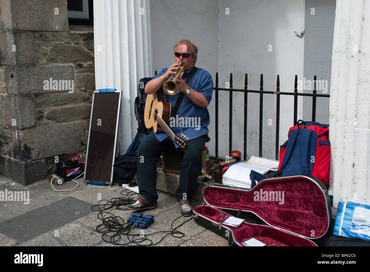 A busker performing in Falmouth, using solar cells and inverter for power Stock Photo