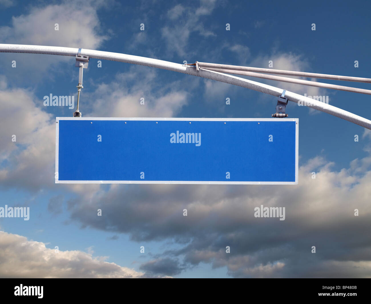 Large, blank, blue, hanging street sign with dramatic clouds. Stock Photo
