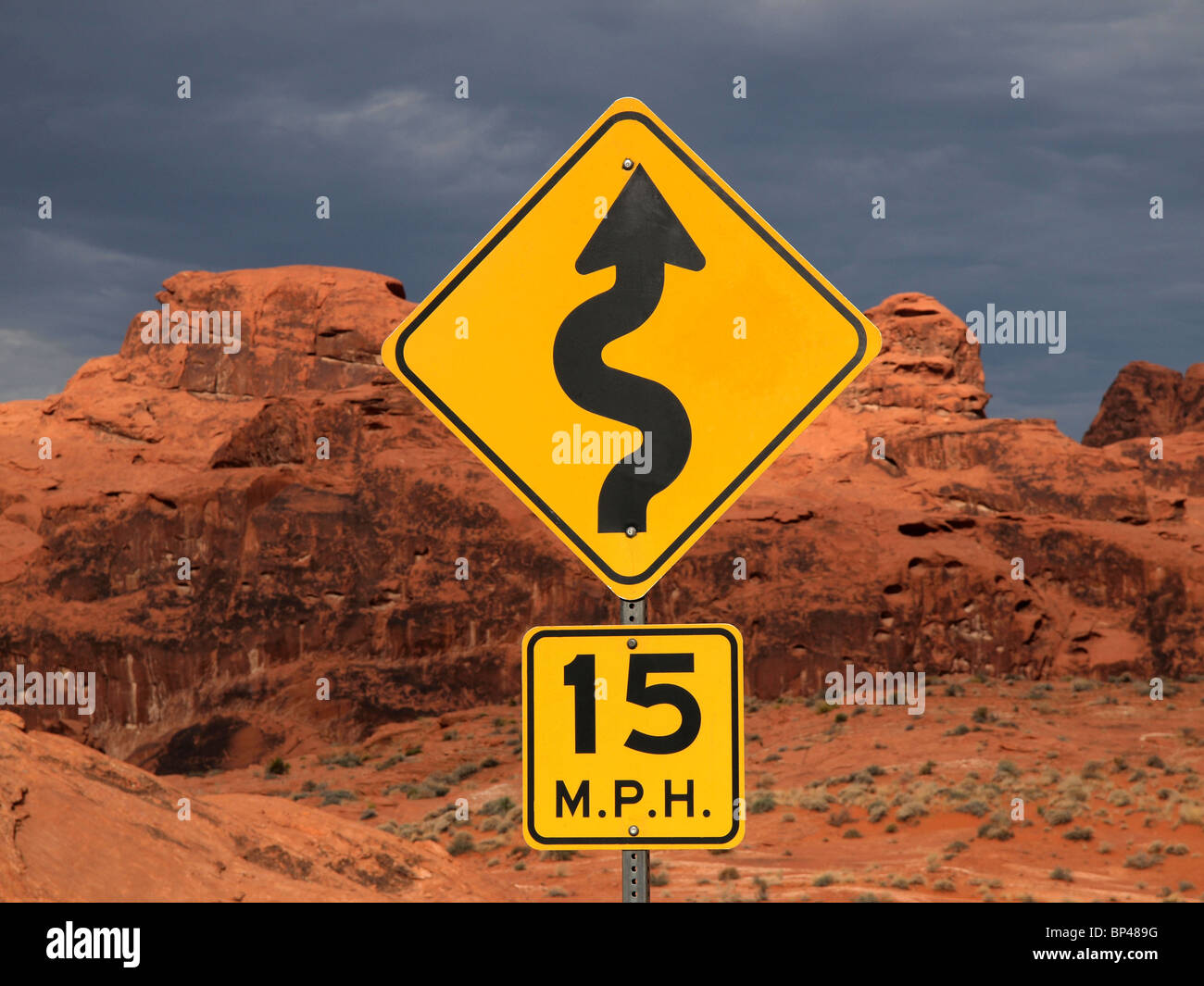 Curve sign against red desert cliffs at sunset. Stock Photo