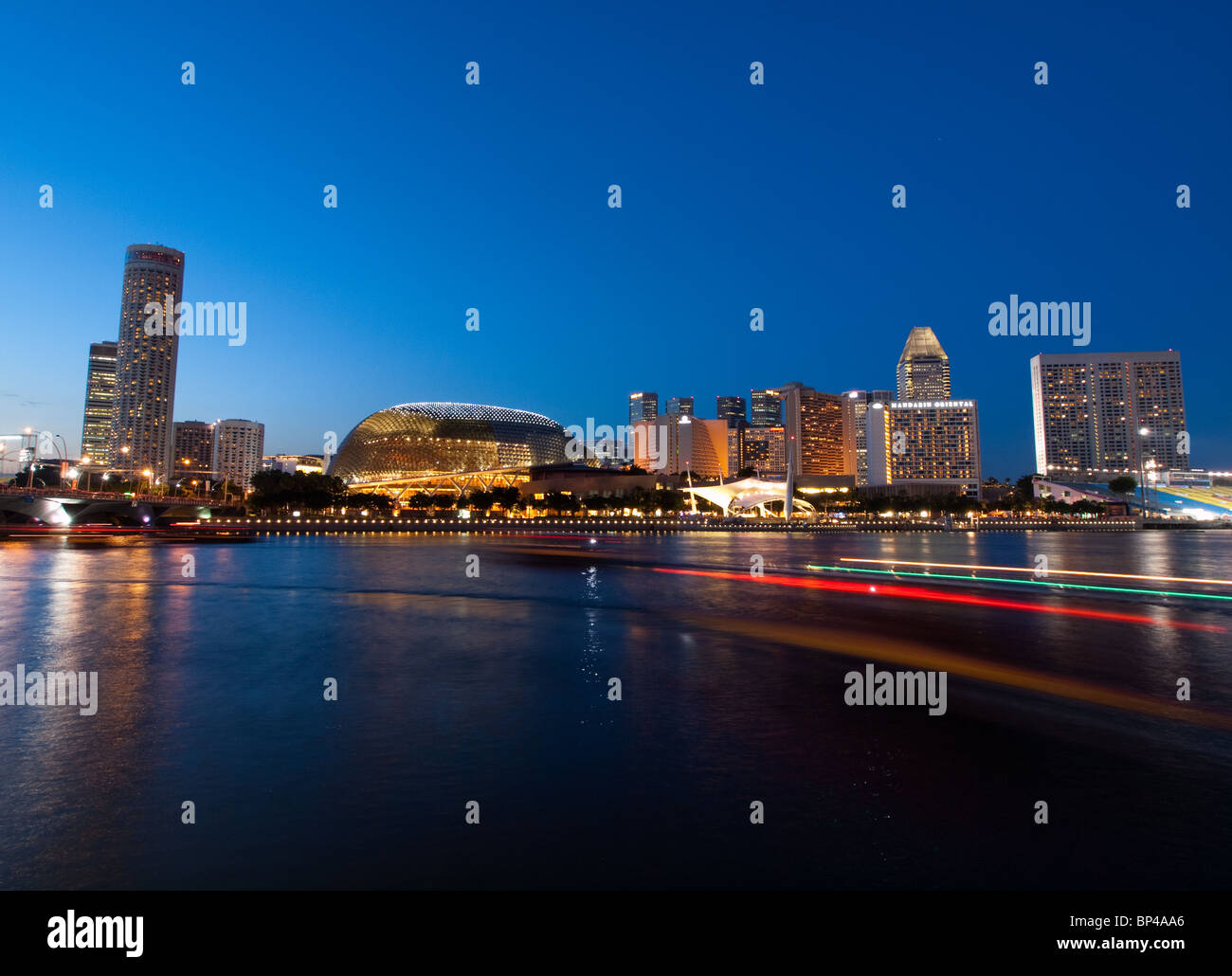 The beautiful Esplanade Singapore at night, with a ferry whizzing by. Stock Photo