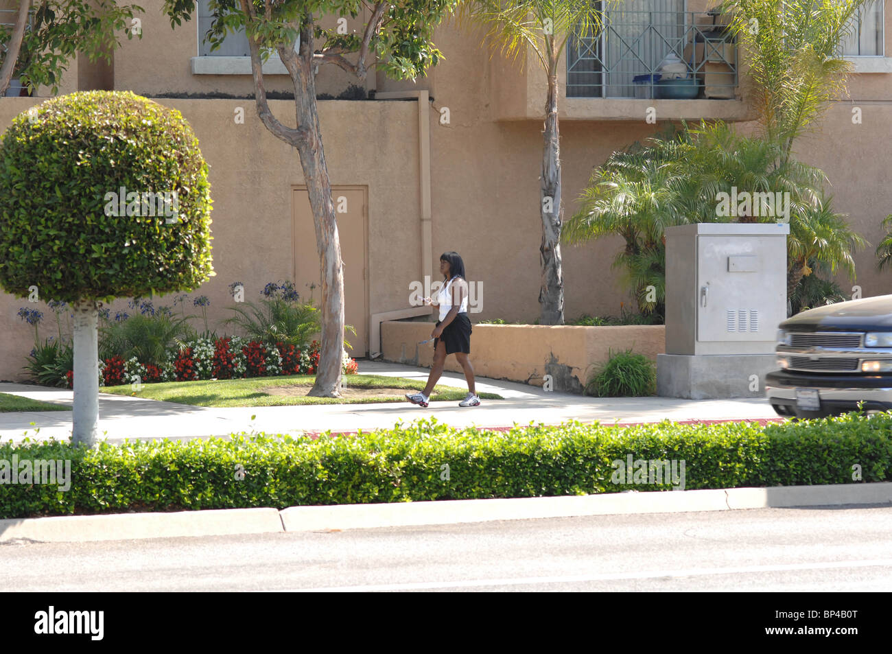 African American Woman walking on the sidewalk wearing athletic clothing. Stock Photo