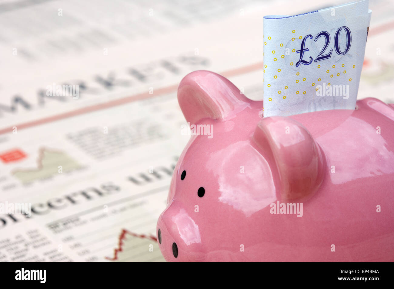 pink piggy bank with 20 pound note sitting on a copy of the financial times newspaper money markets section in the uk Stock Photo