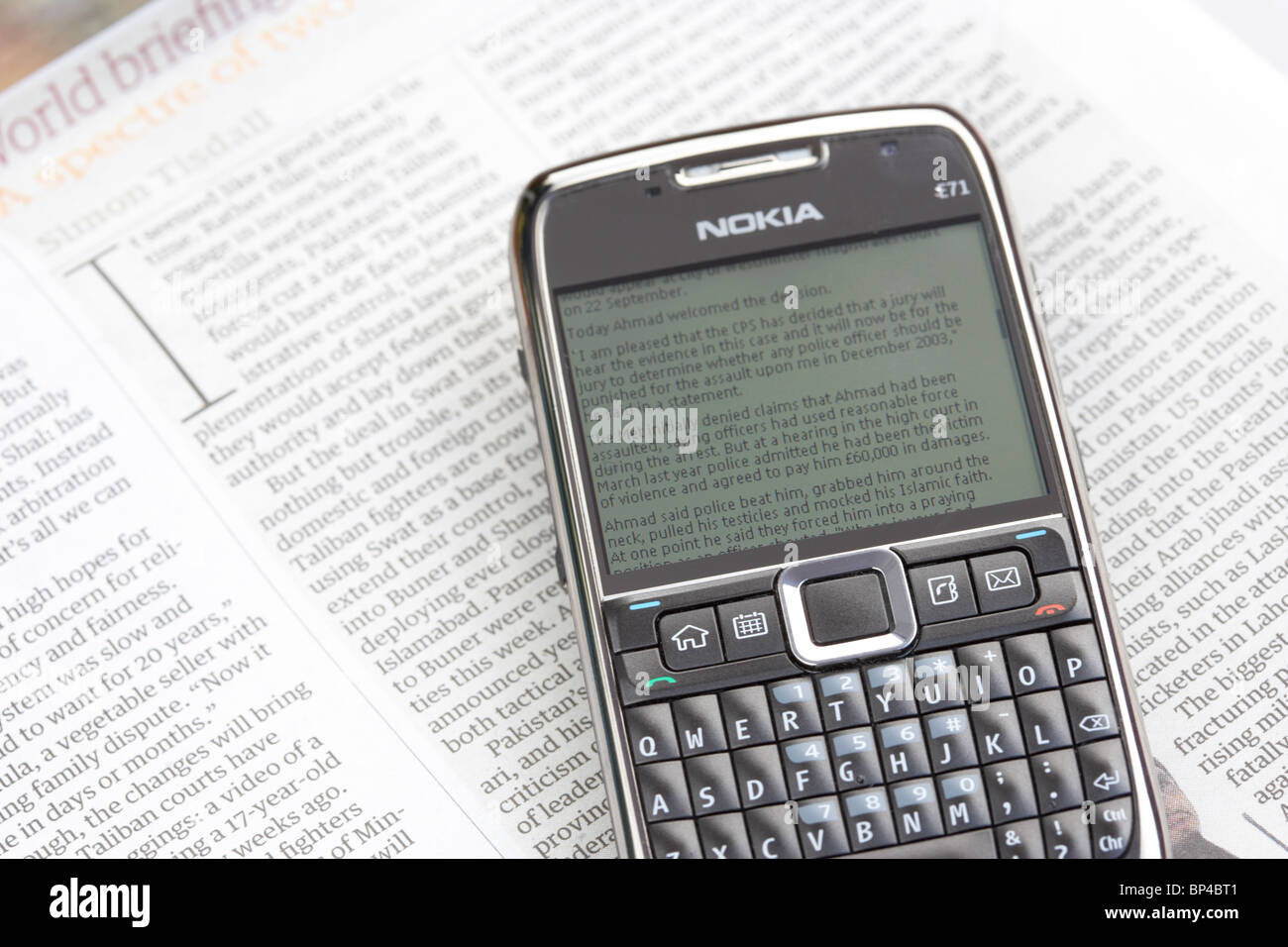 smartphone displaying latest online newspaper website news lying on the printed version of the newspaper Stock Photo