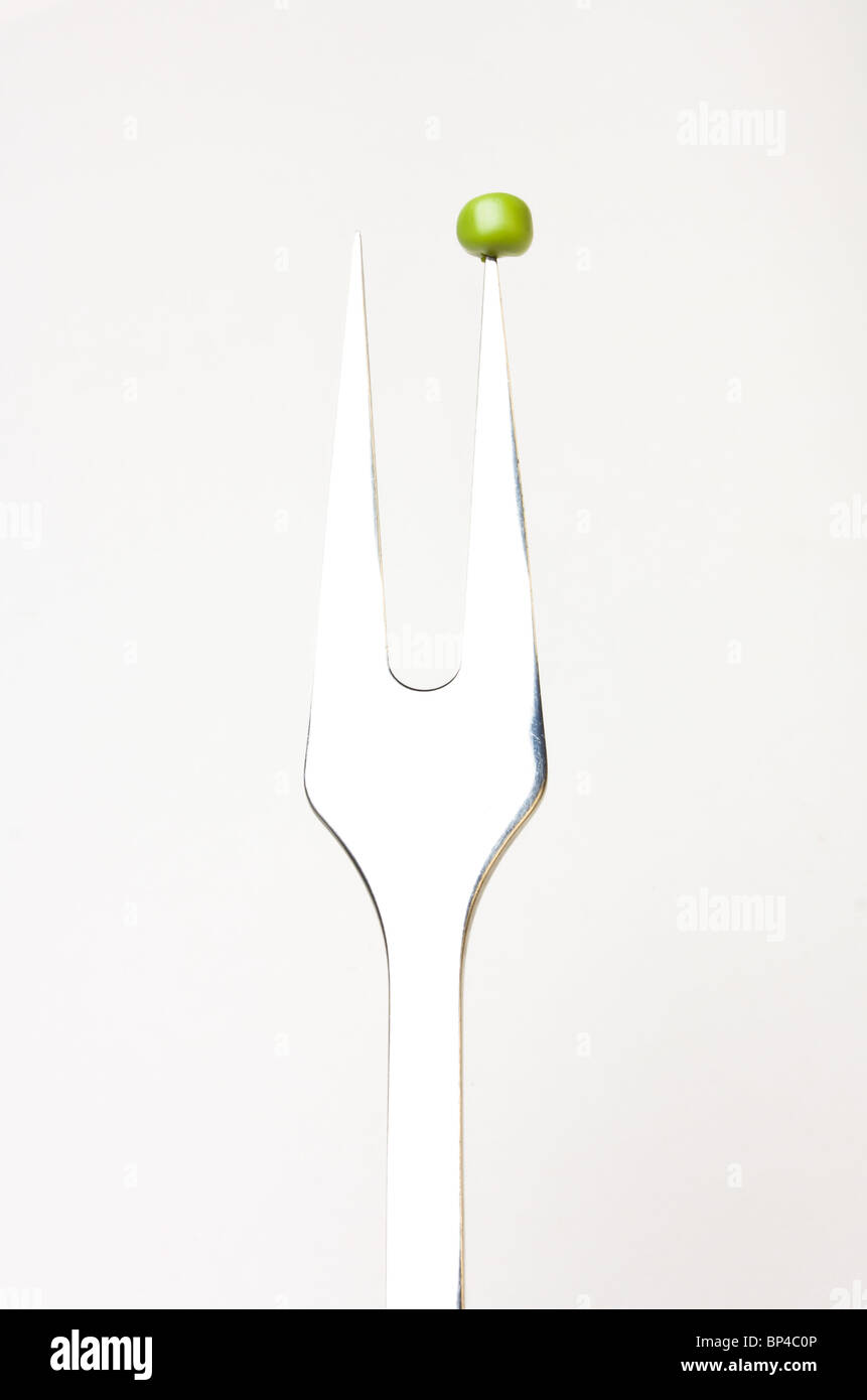 Abstract image of single pea on fork concept isolated against white. Stock Photo