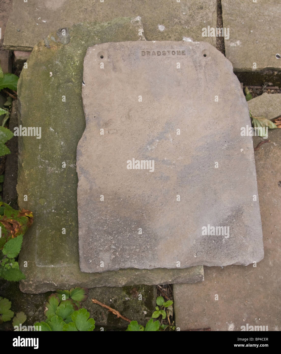An artificial stone roofing slab (manufactured by Bradstone) sitting on top of a roof slab of natural stone. Stock Photo