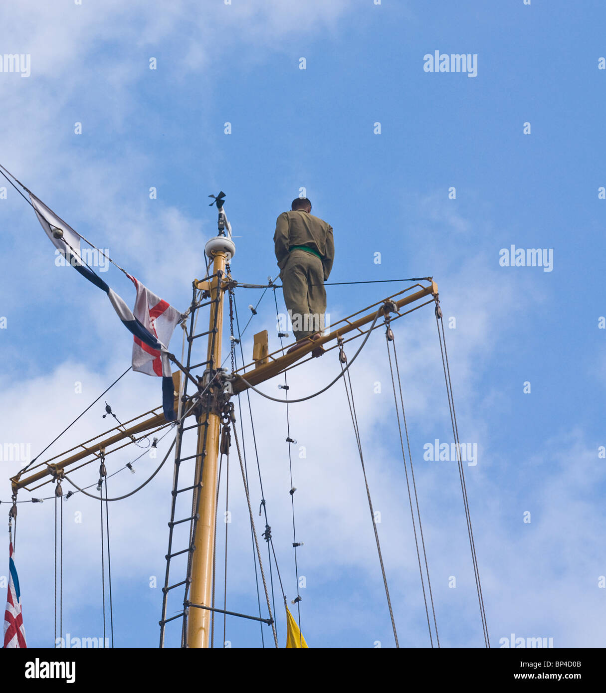 crewman standing on the top yard of the rear mast of a barquentine sailing ship (The Dewaruci) Stock Photo