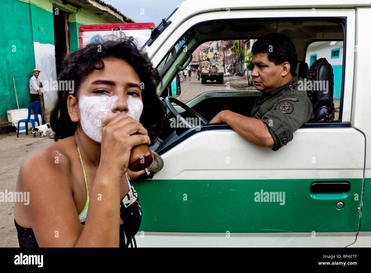 A young girl getting high by sniffing the shoe glue in front of the Police patrol in the slum of Calvario, Cali, Colombia. Stock Photo